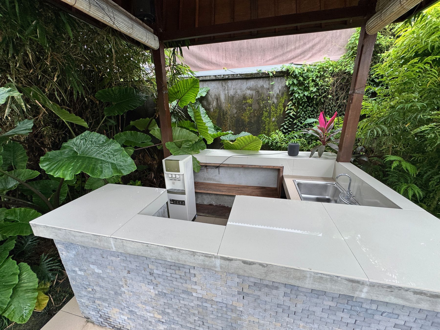 The outdoor kitchen bench under a thatched roof, surrounded by tropical plants