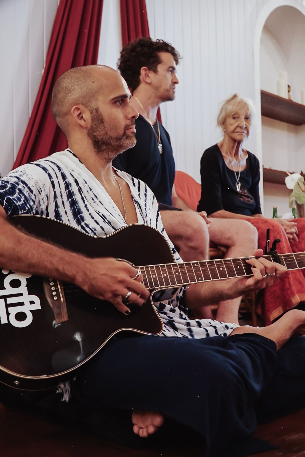 A man playing guitar in a seated circle, others listening beside him