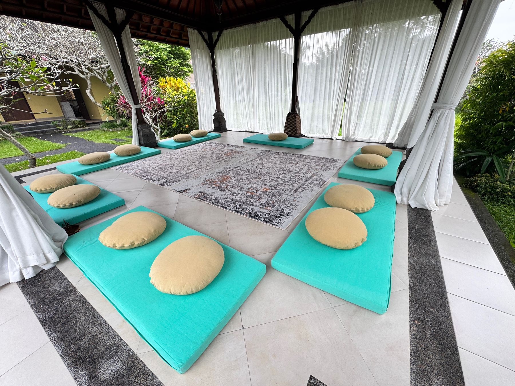 Inside Kali Shala: floor cushions around a rug, curtains open to the garden