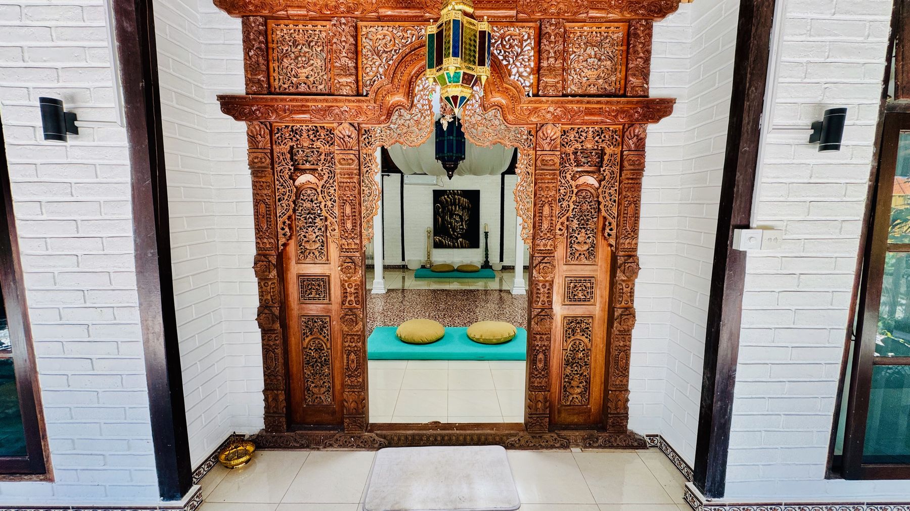 A carved timber doorway at the end of Shivatri Temple, white walls either side