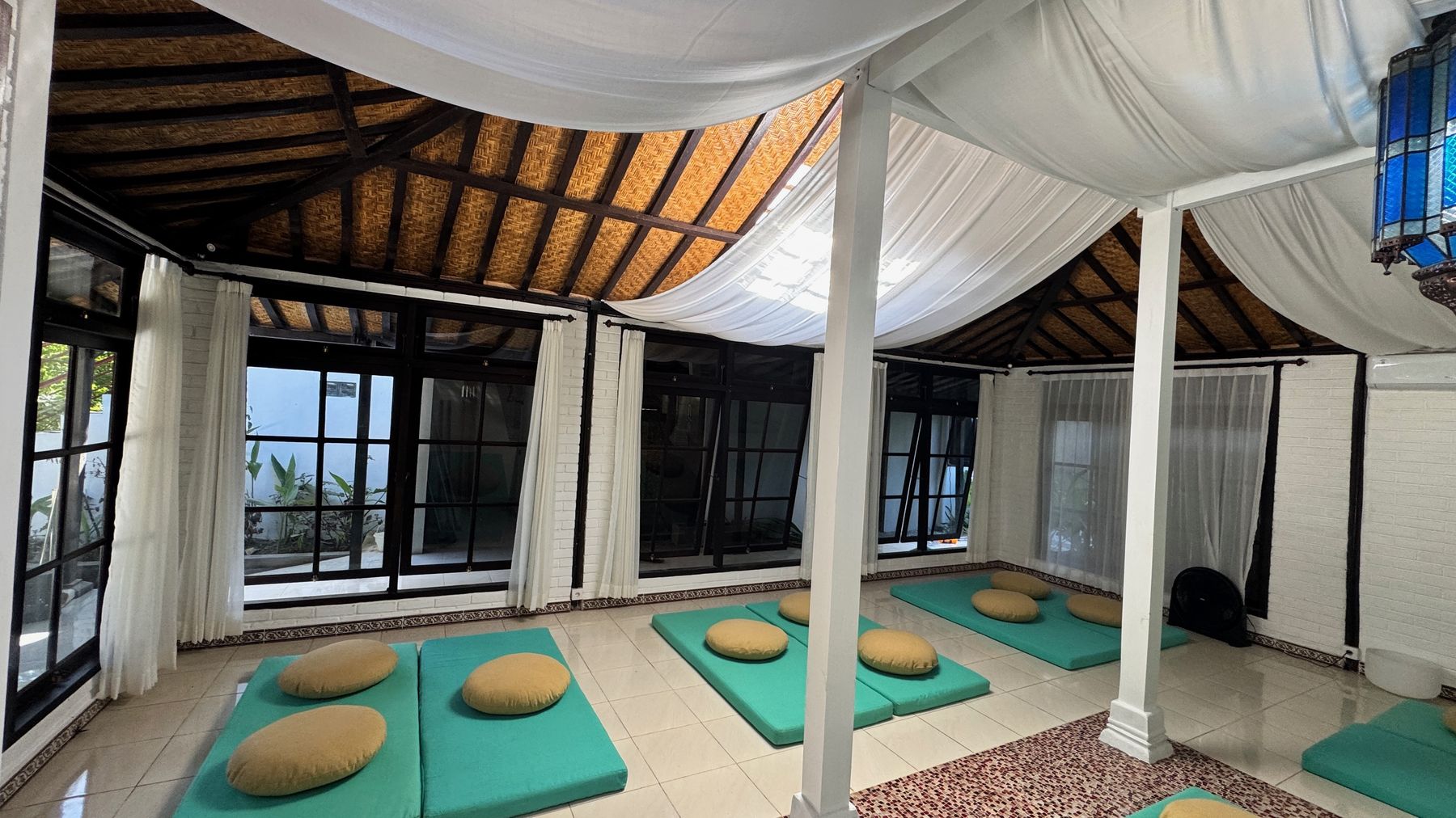 Shivatri Temple from one corner, windows along the wall and cushions on the floor